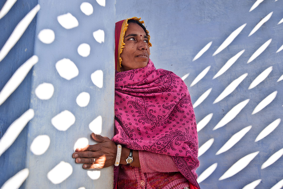 woman in pink sari in india against a blue wall