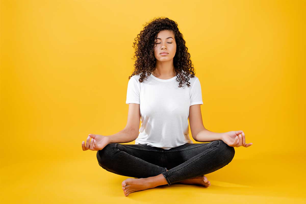 woman sitting on ground with yellow background in white t-shirt