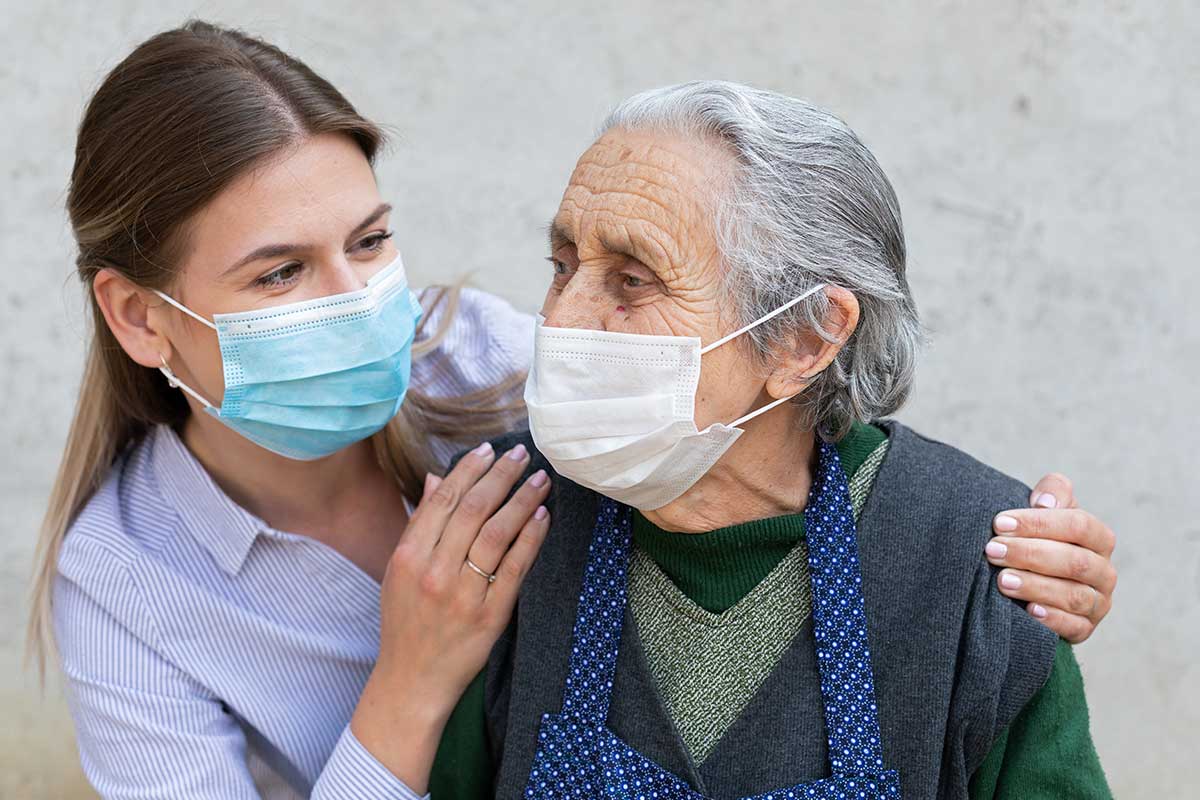 woman with older adult with blue and white face masks
