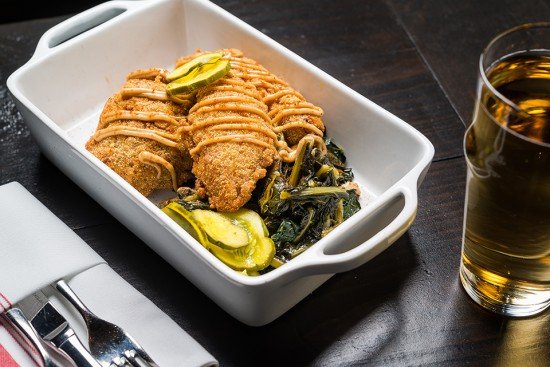 Fried chicken drizzled with a black garlic-miso aioli, paired with pickles and kale.
