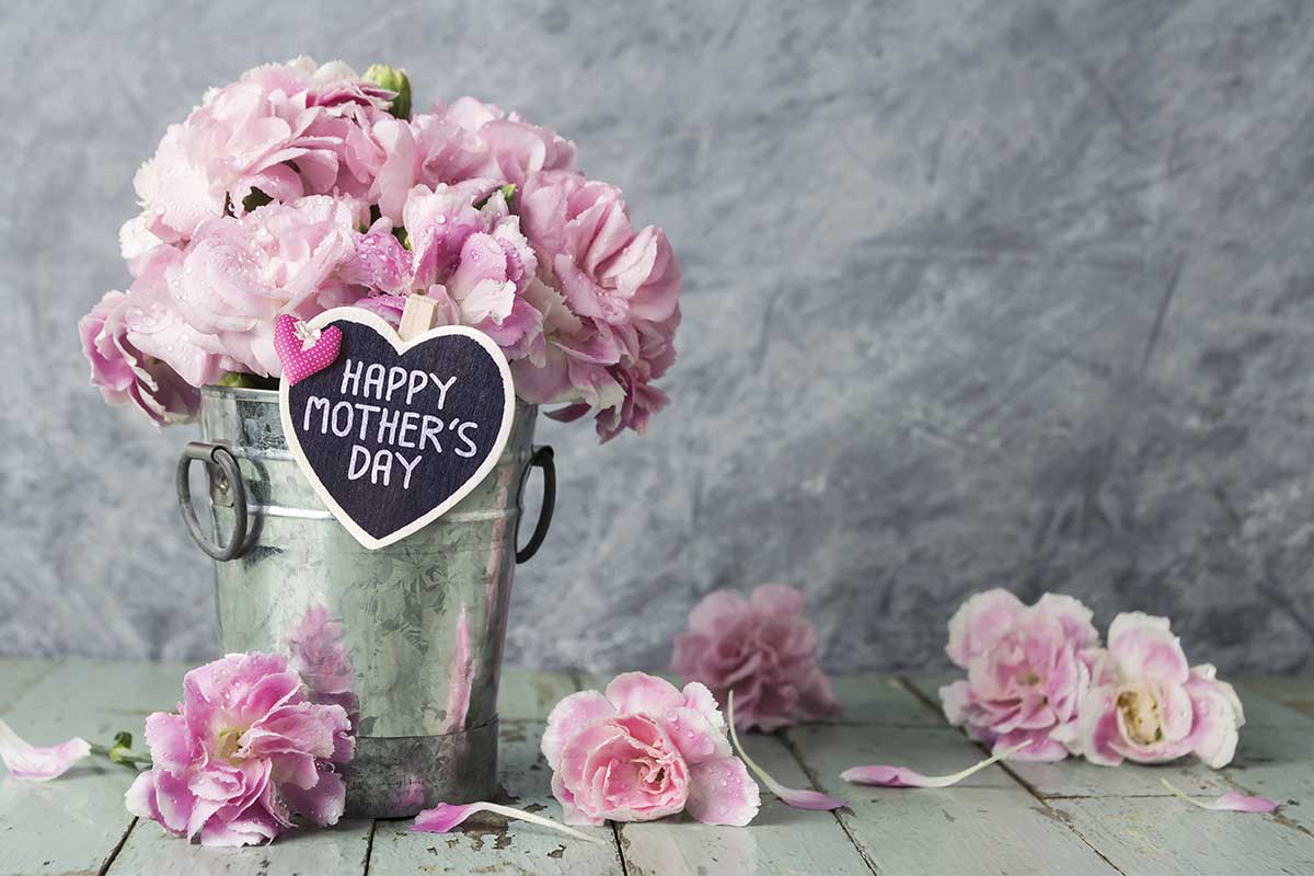 pink flowers in a silver bucket with sign that says happy mothers day