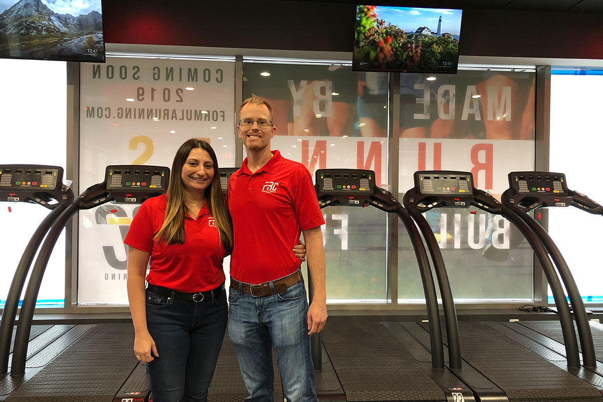 formula running center owners wearing red shirts in front of treadmills