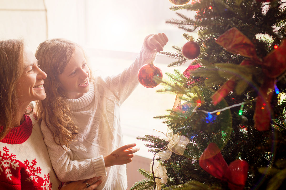 mom and kid putting ornament on tree