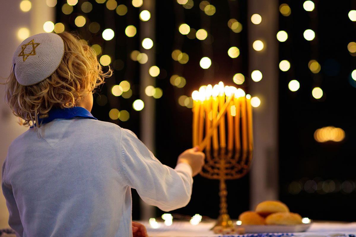 young boy lighting menorah