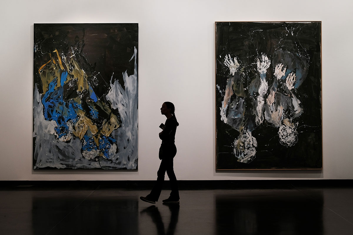 girl walking in art exhibit with two large paintings