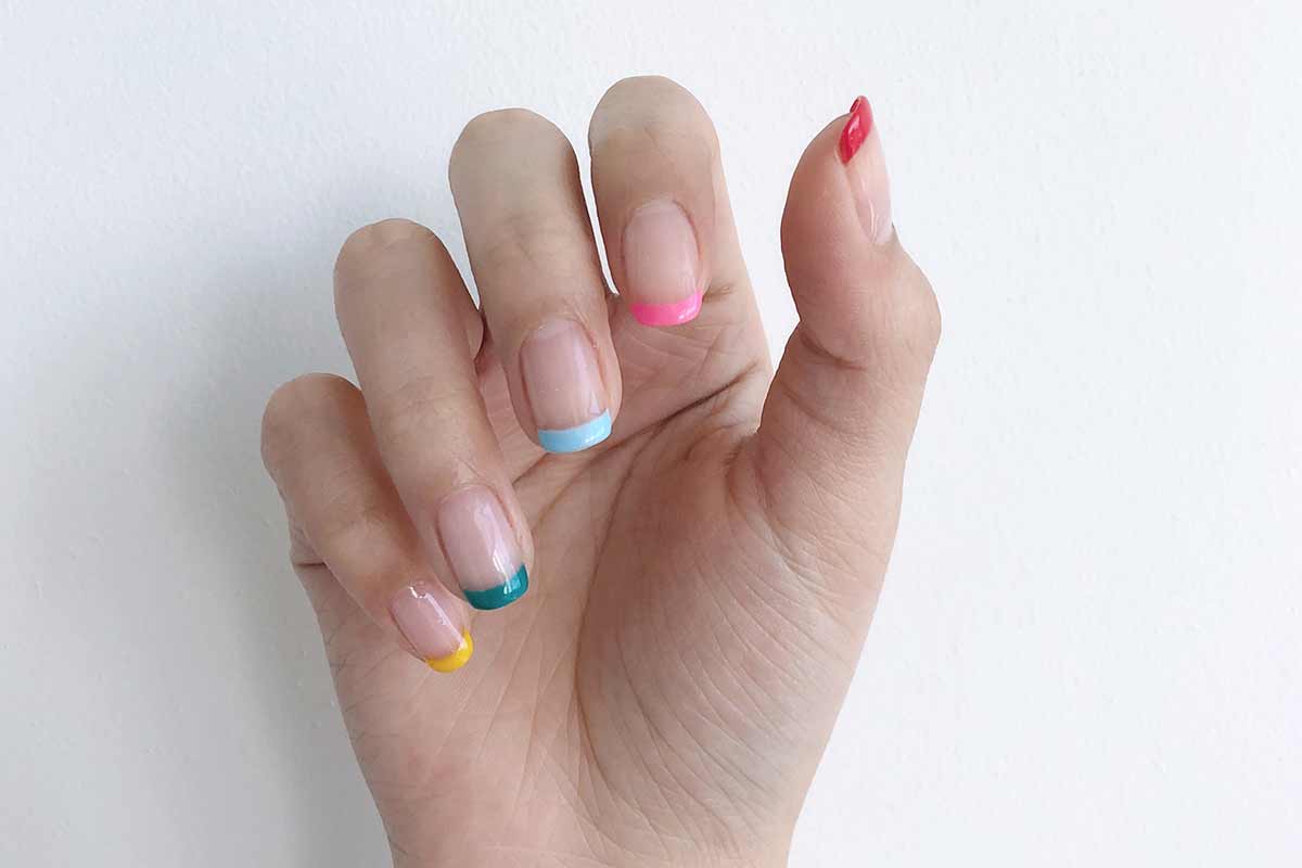 french manicure on hand with rainbow painted nails