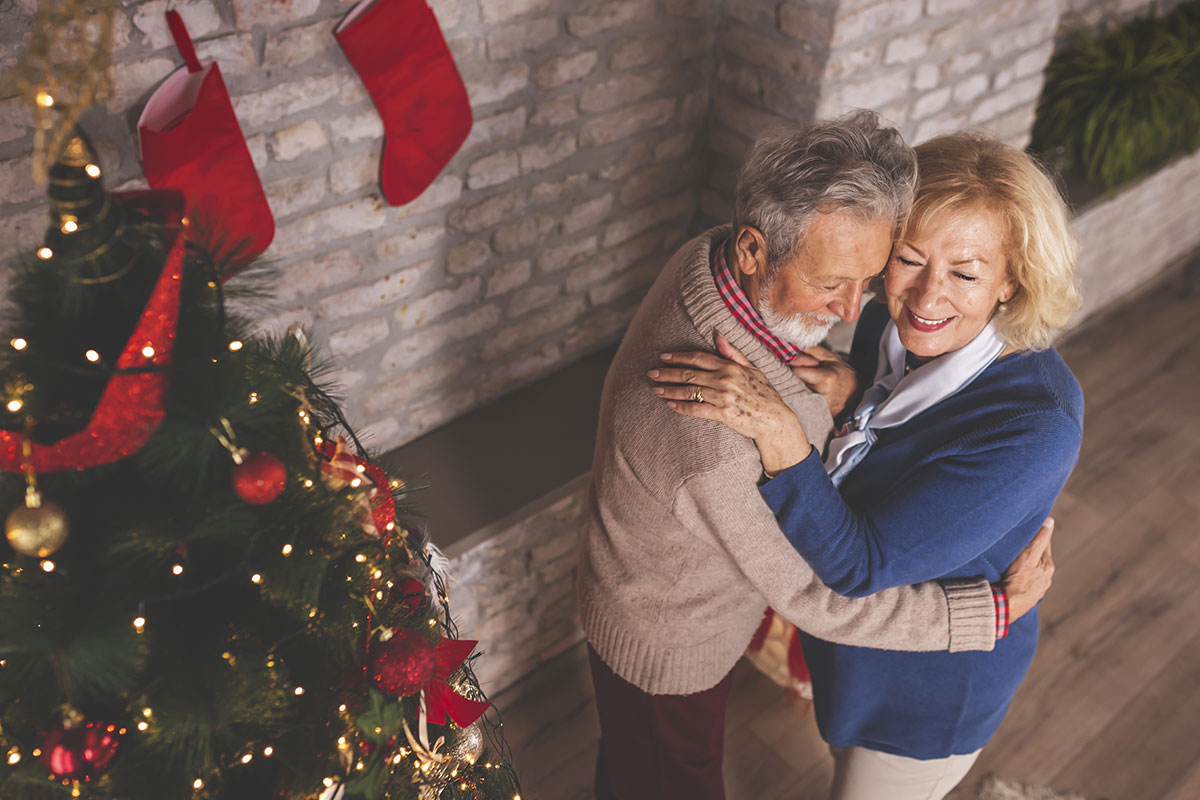 senior man and woman dancing near christmas tree