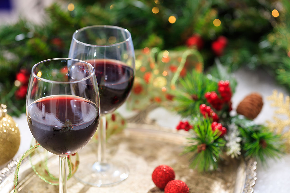 two glasses of red wine on table with green fern