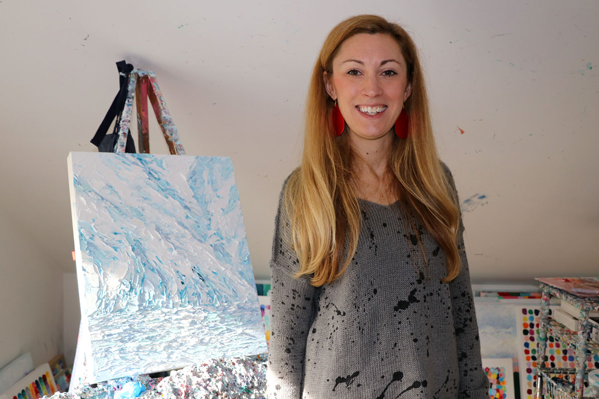 woman in grey sweater standing by painting