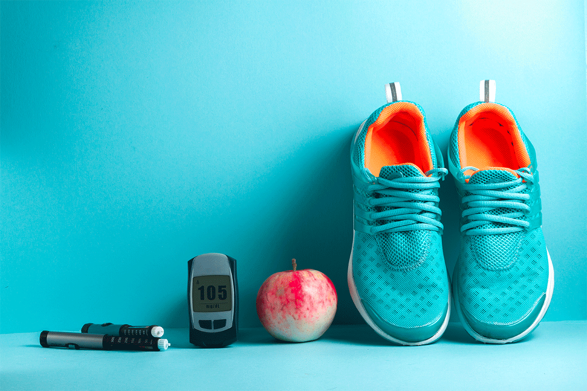 diabetes monitor next to an apple and sneakers against a blue wall