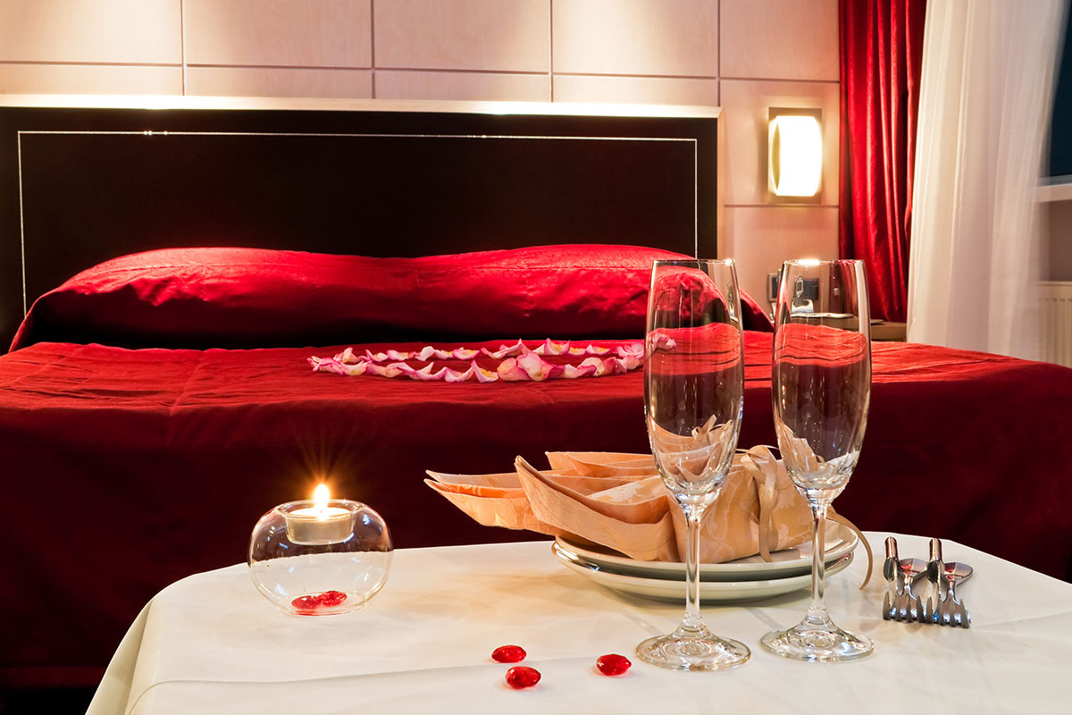 hotel bed with rose petals and champagne glasses