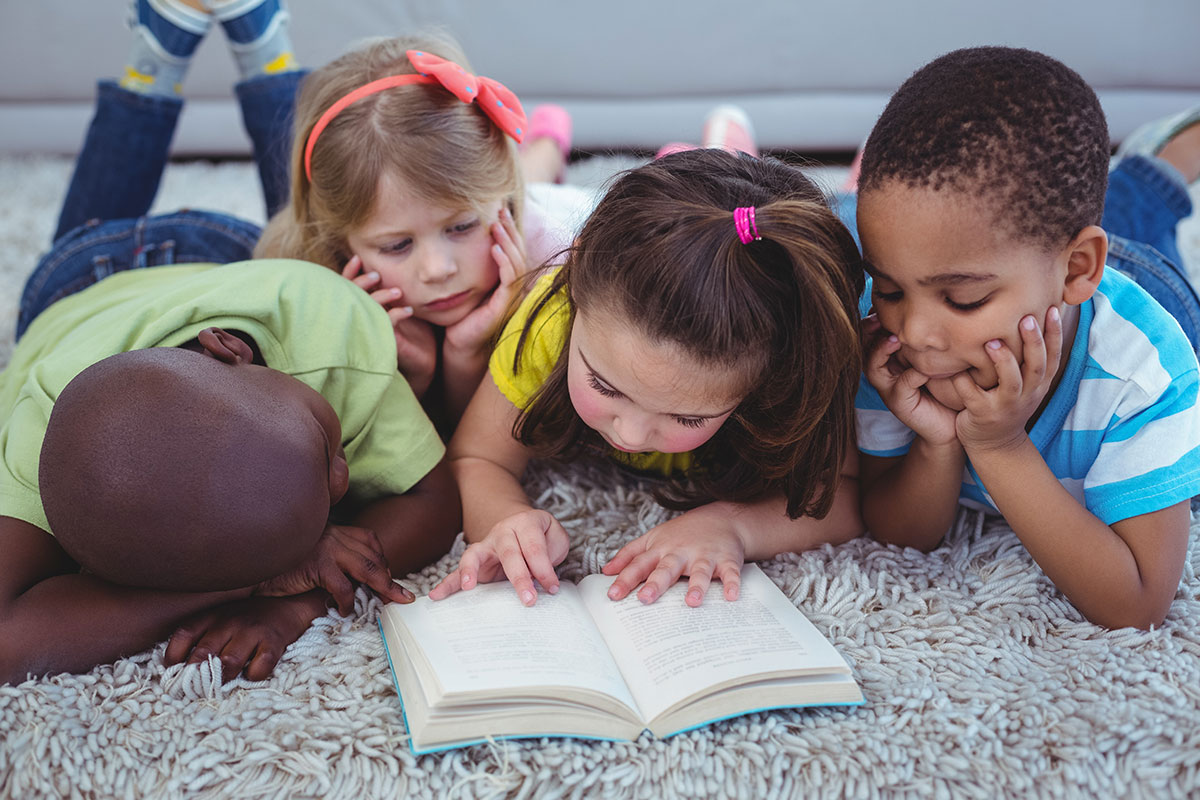 kids reading book on floor with two boys and two girls