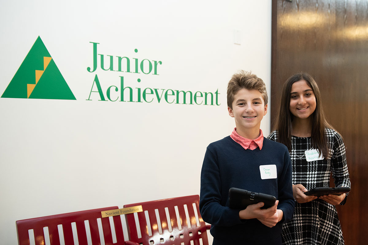 boy and girl in front of "junior achievement" wall