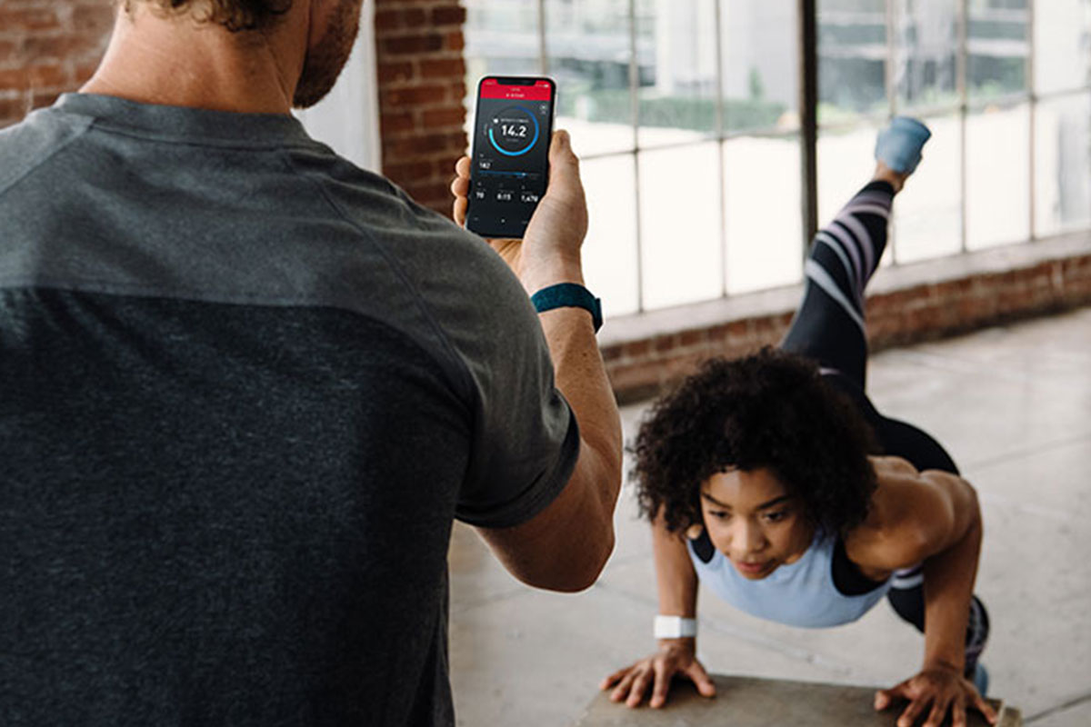man looking at phone while woman is doing yoga pose