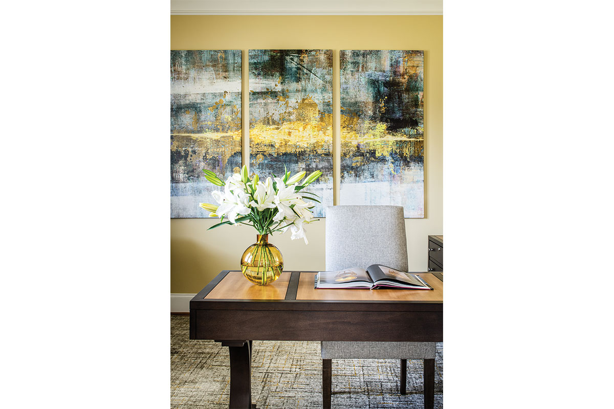 home office with yellow and gray and white paintings with flowers in vase and book