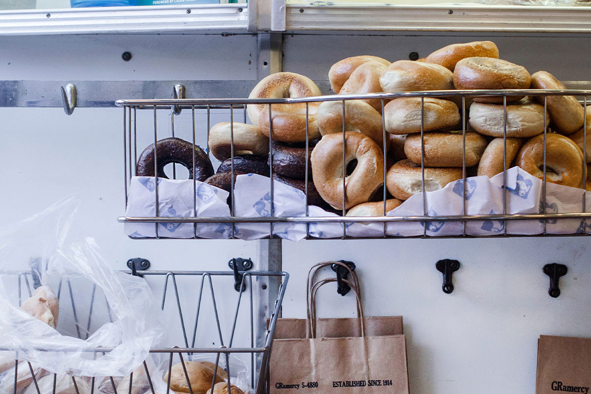 basket of bagels in front of white wall with paper bag