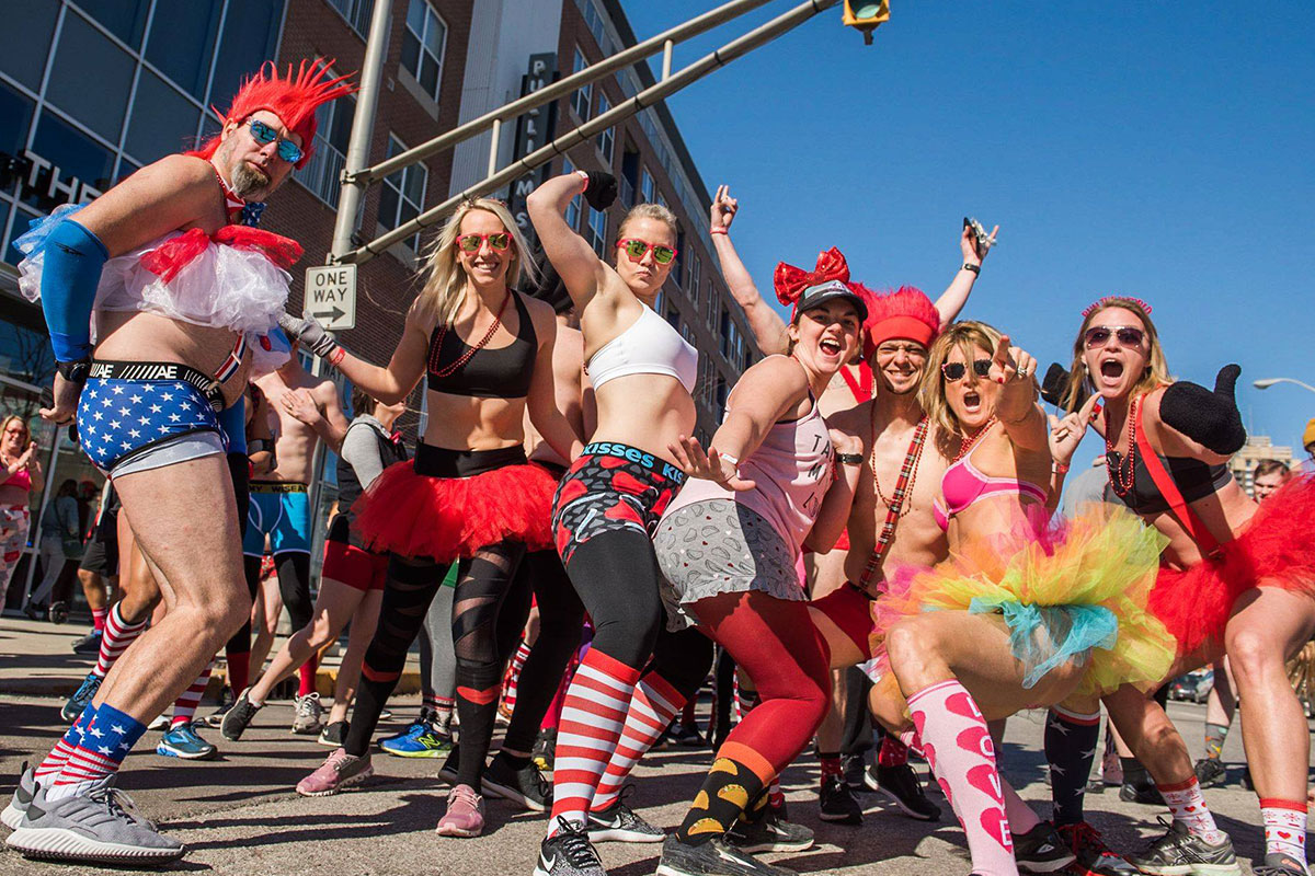 men and women in tutus and underwear outside running with lots of color