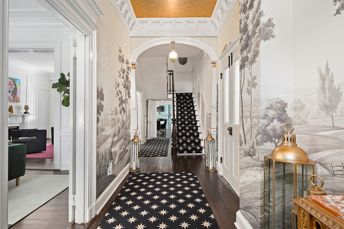 entryway with gray wallpaper and black staircase