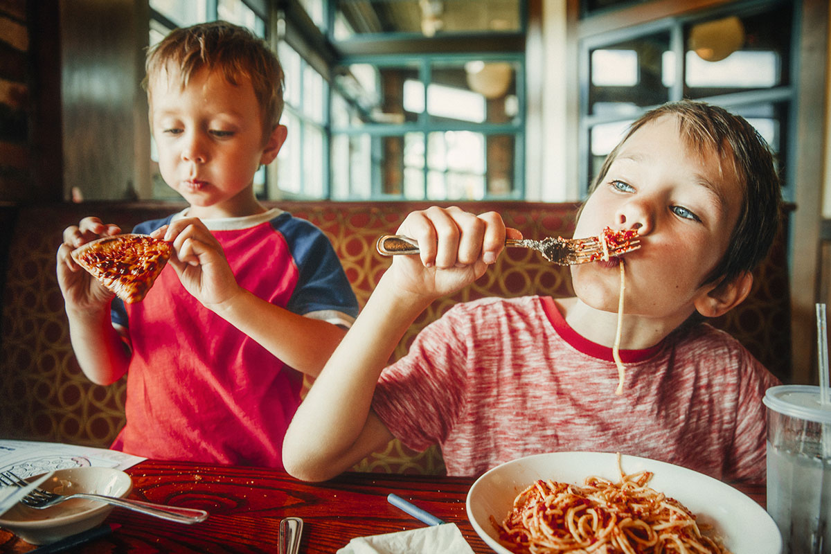 kids eating pizza and spaghetti in a restaurant