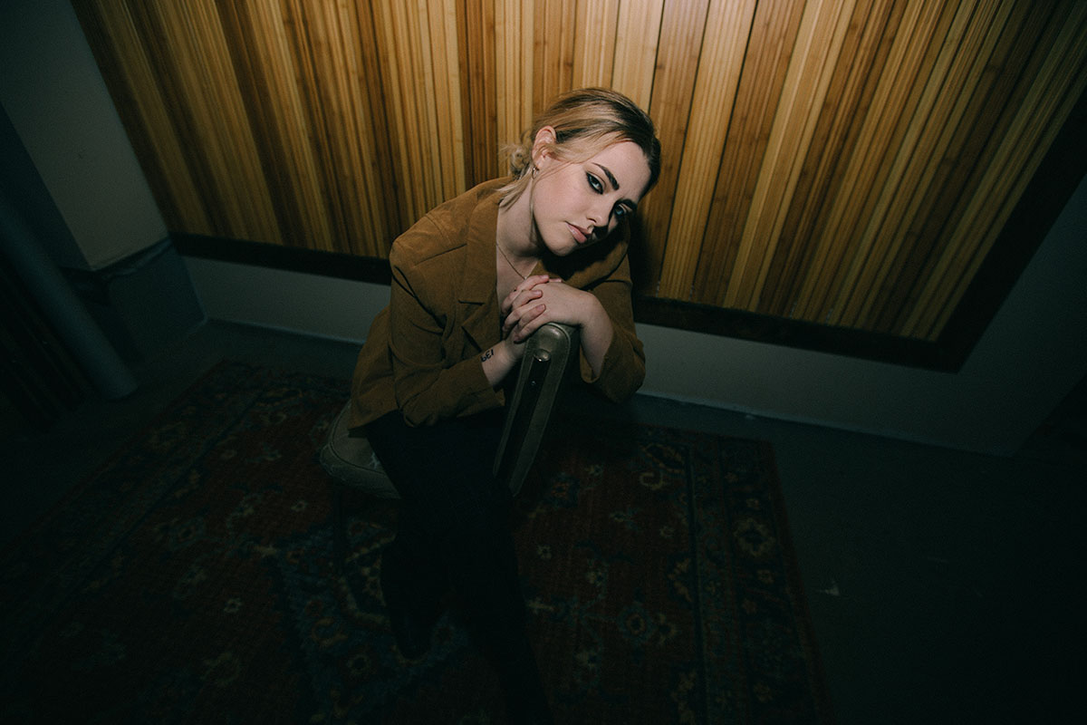 maggie miles in brown blazer in front of wood wall