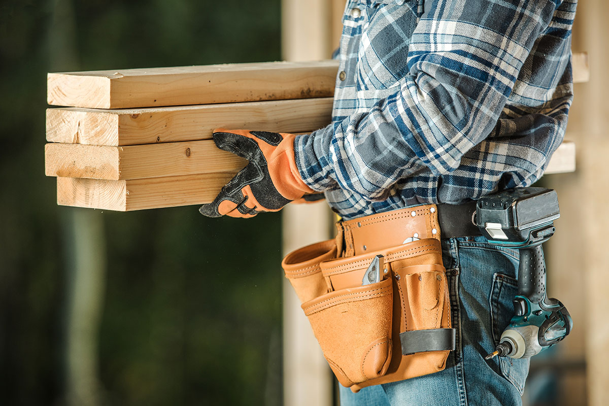 man with wooden beams and contractor belt
