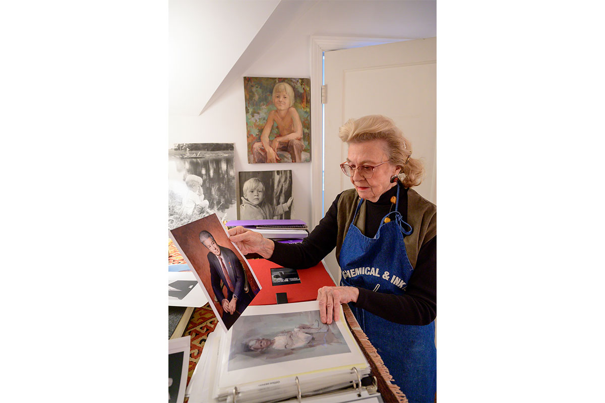 Nancy Hersch Ingram in her home studio holding up artwork