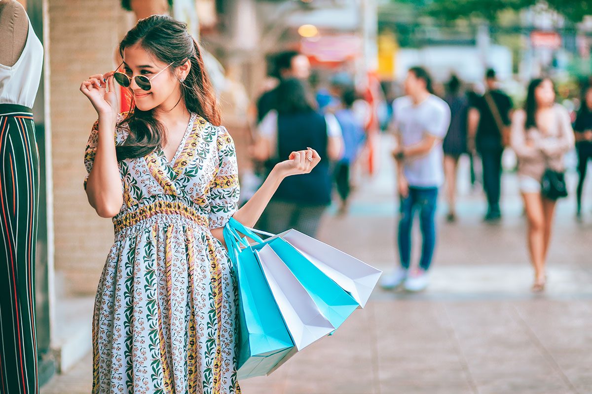 woman with shopping bags touching sunglasses