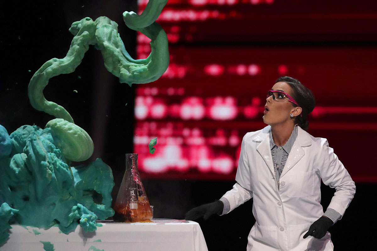 miss america performing a science experiment with green foam in a white lab coat