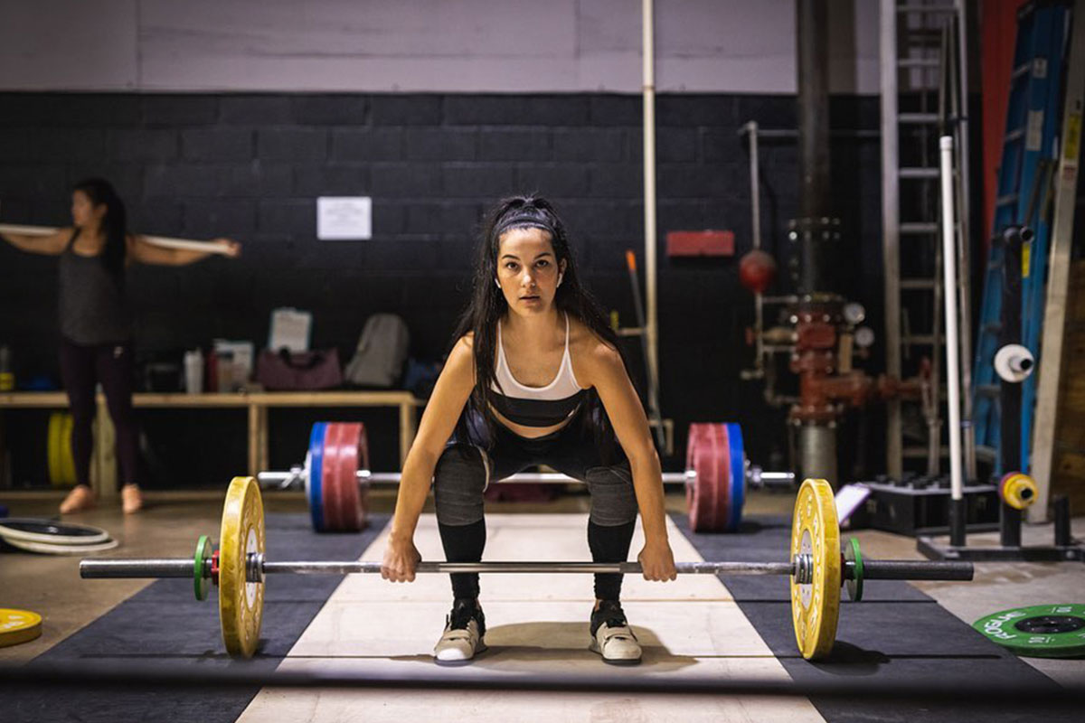 woman lifting barbell with yellow weights