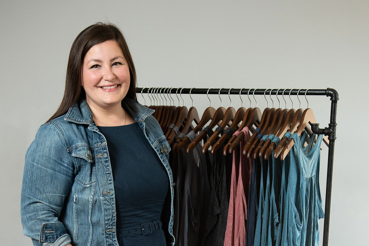 woman zoomed in standing in front of clothing rack