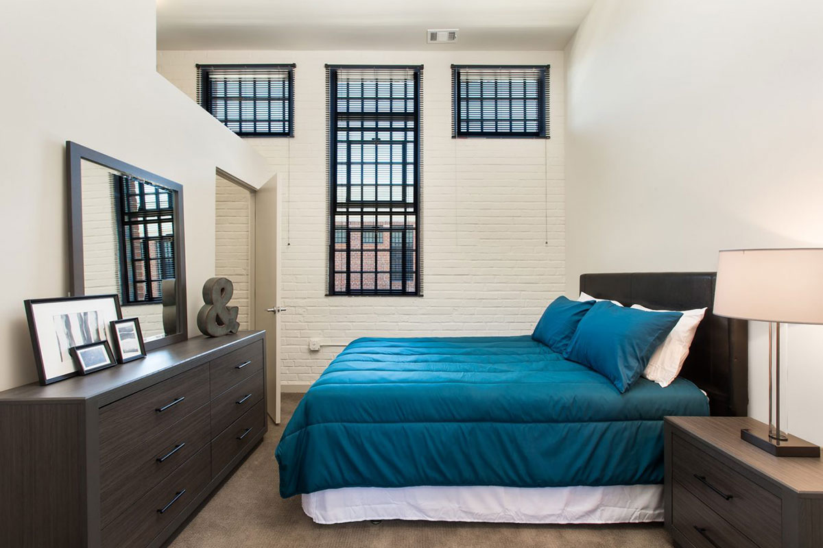 blue bed in white brick walled room