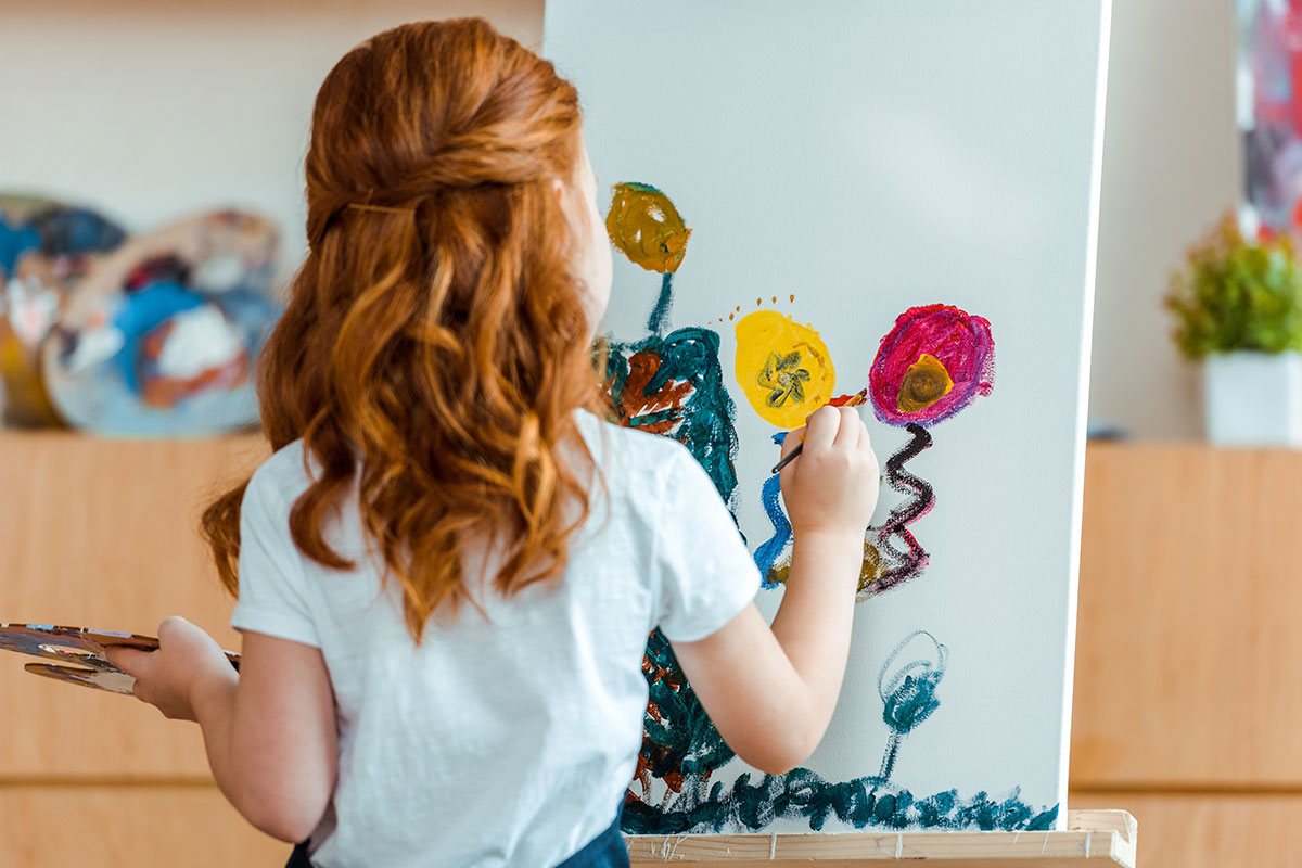little girl with red hair doing art at art camp