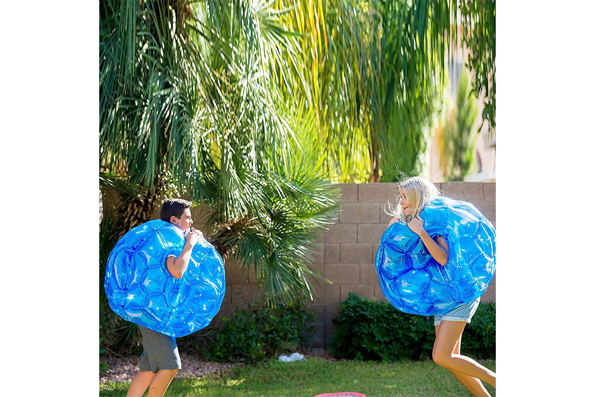 two people wearing blue inflatable balls for playing in the backyard with family