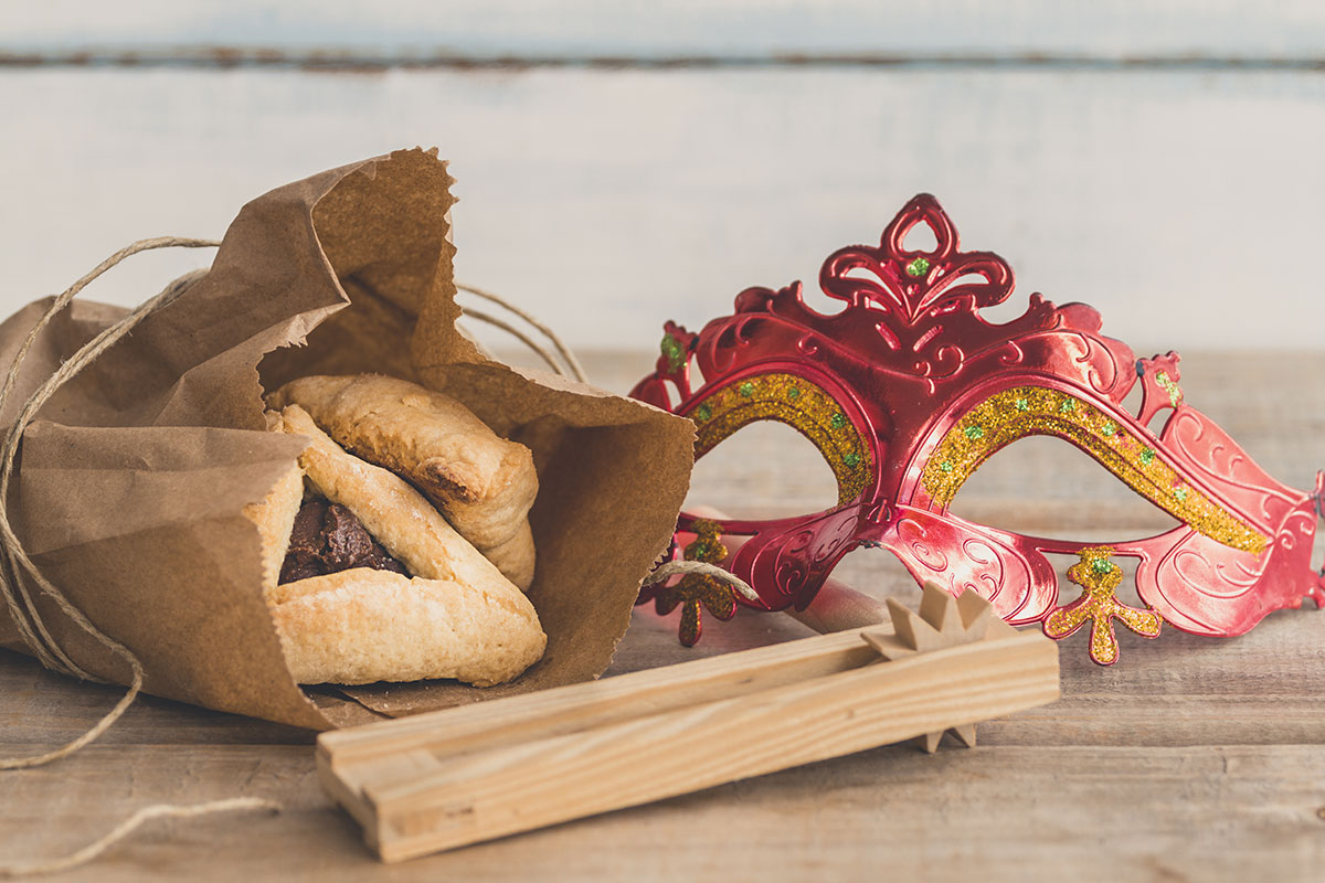 purim mask and noisemaker and pastry