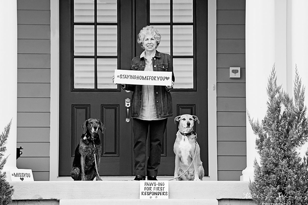 woman with two dogs on porch, holding sign