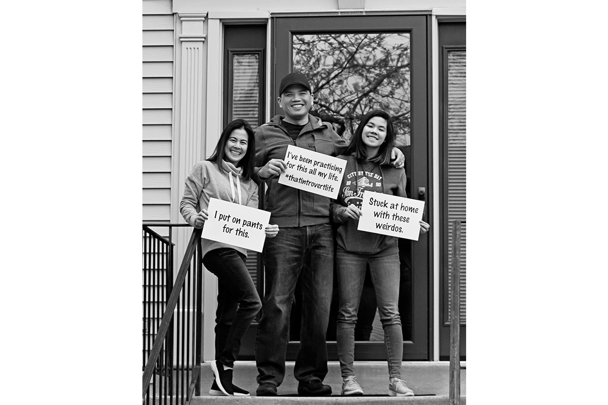 two woman and man on porch holding signs