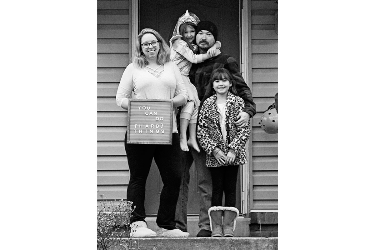 family on their porch in black and white with sign