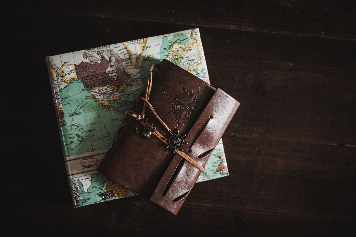 leather book on top of a map travel books