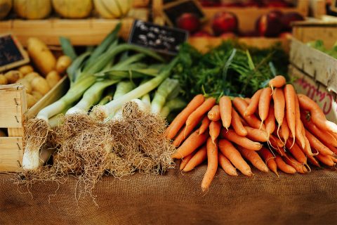 green onions and orange carrots on wood with fruit at farm