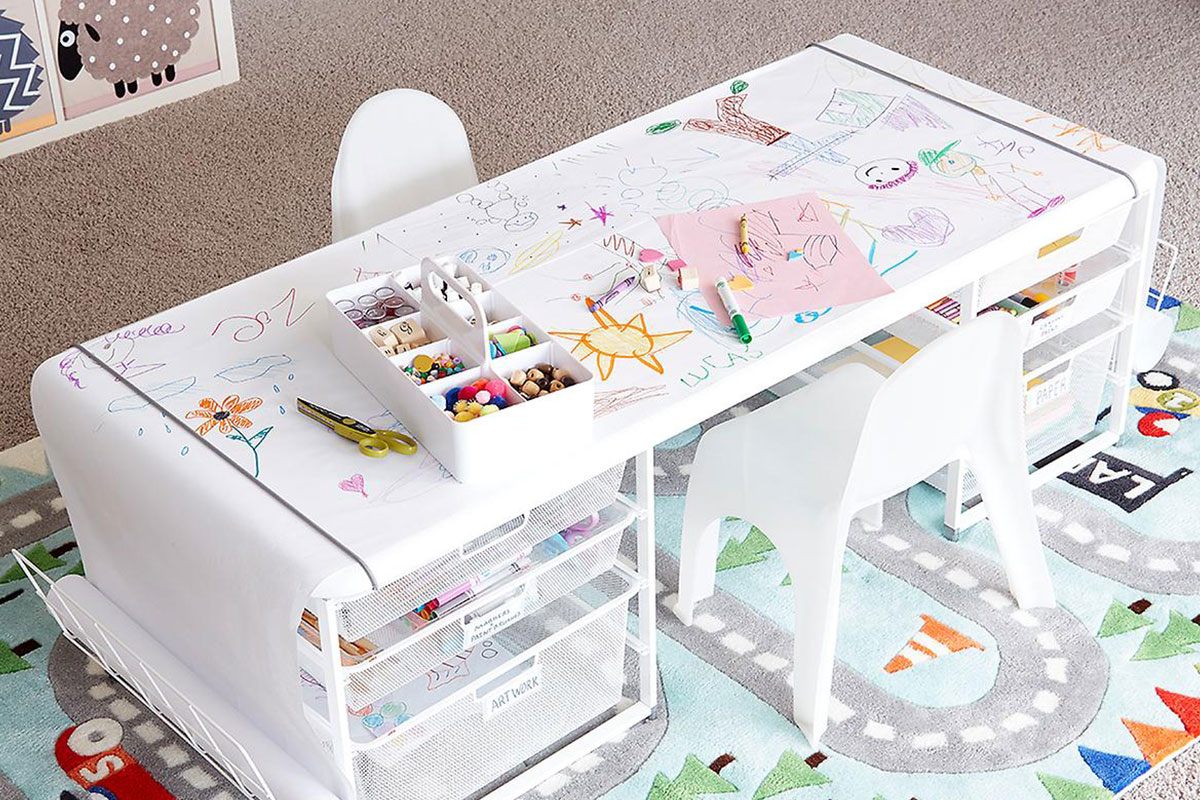 white children's desk with markers and train carpet