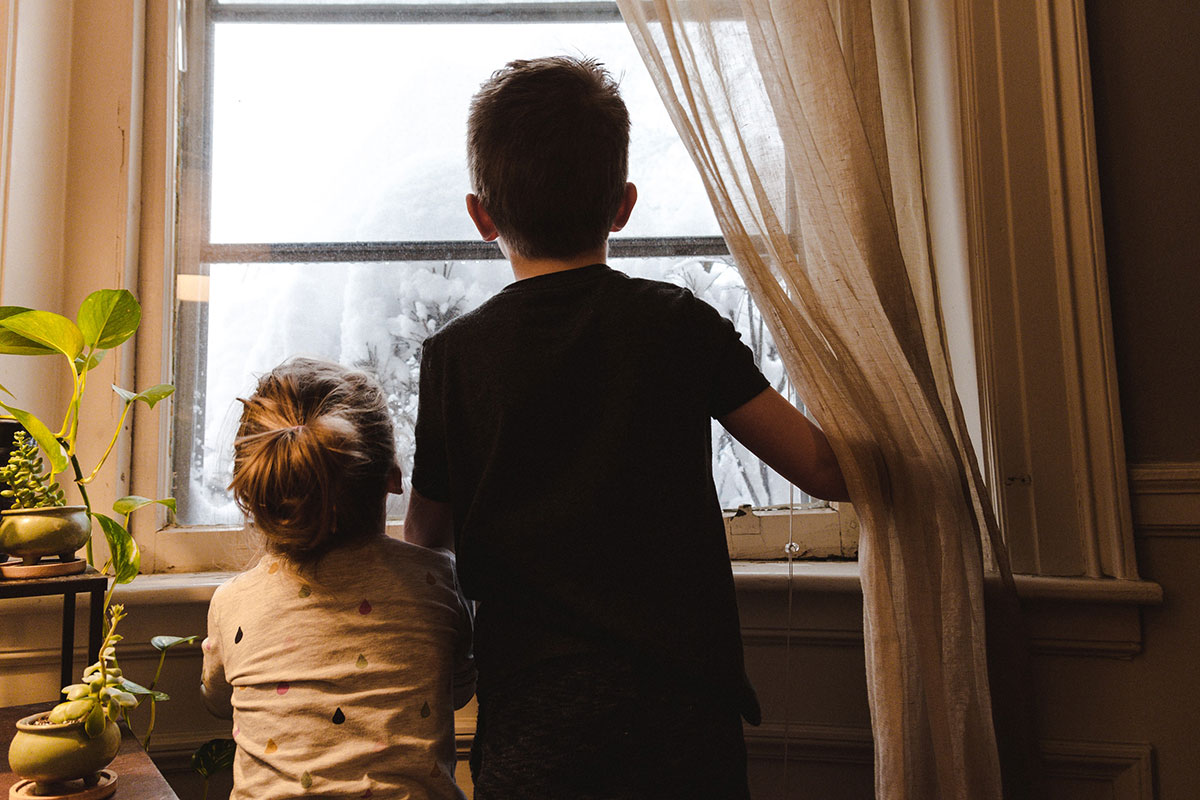 two children looking out their home window