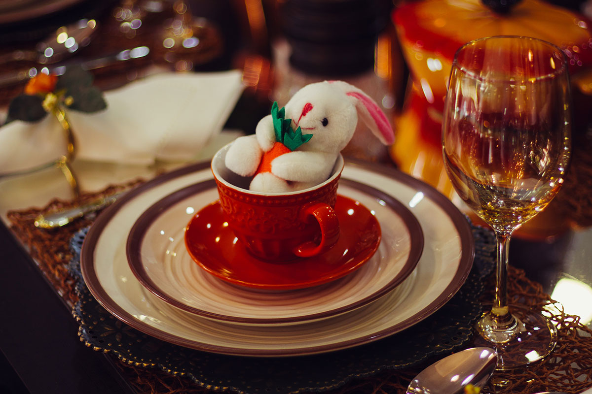 easter bunny doll in cup on a stack of plates at dinner table