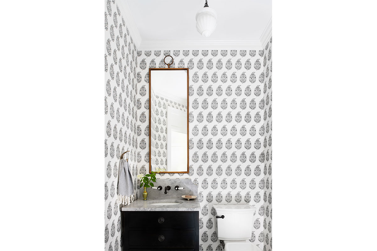 white and balck wallpaper in powder room bathroom with black sink and gold mirror