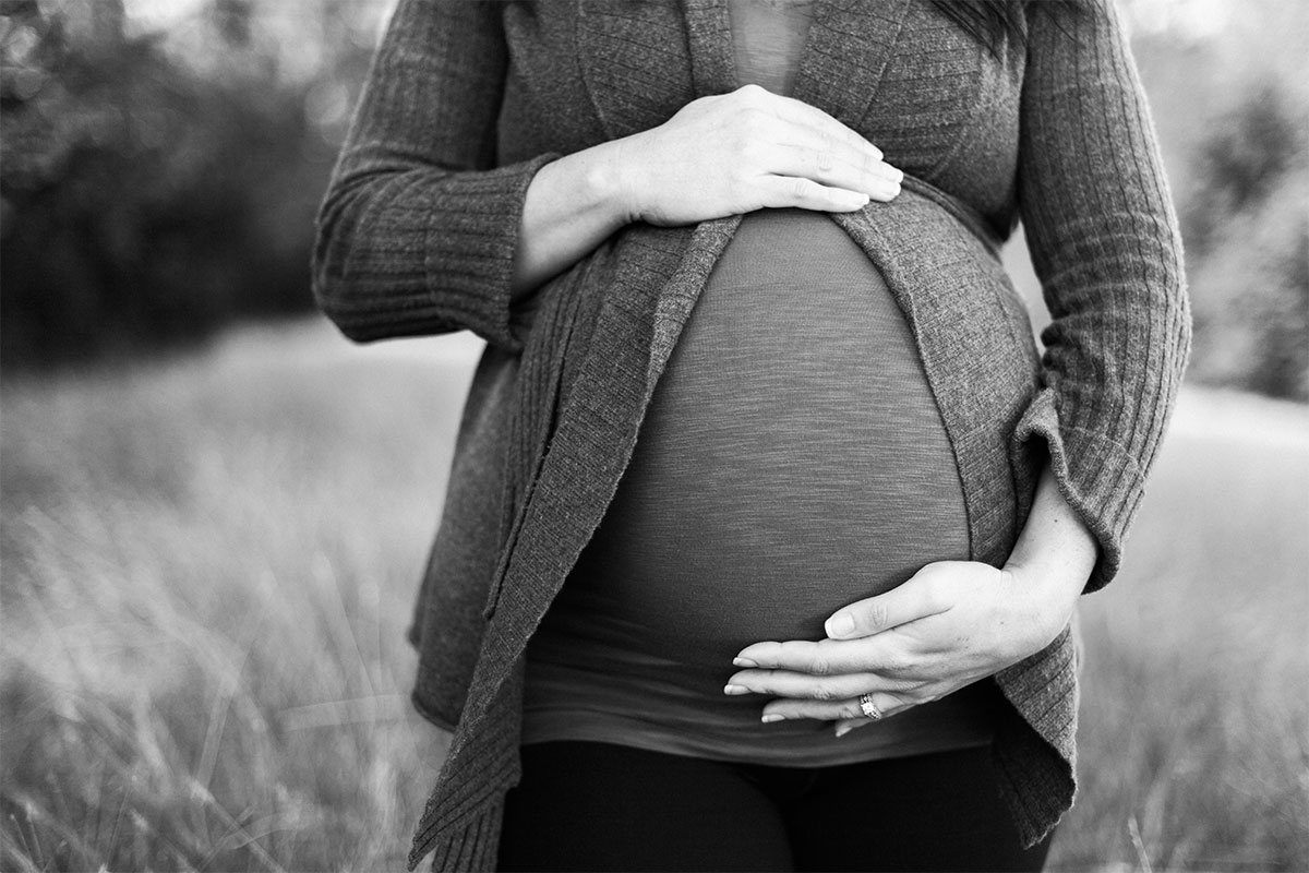 pregnant woman holding belly in grayscale image