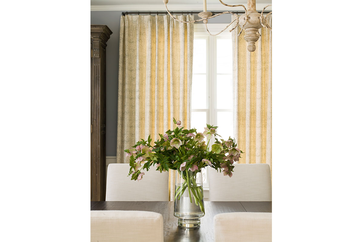 dining room with yellow and white curtains and large bouquet of flowers