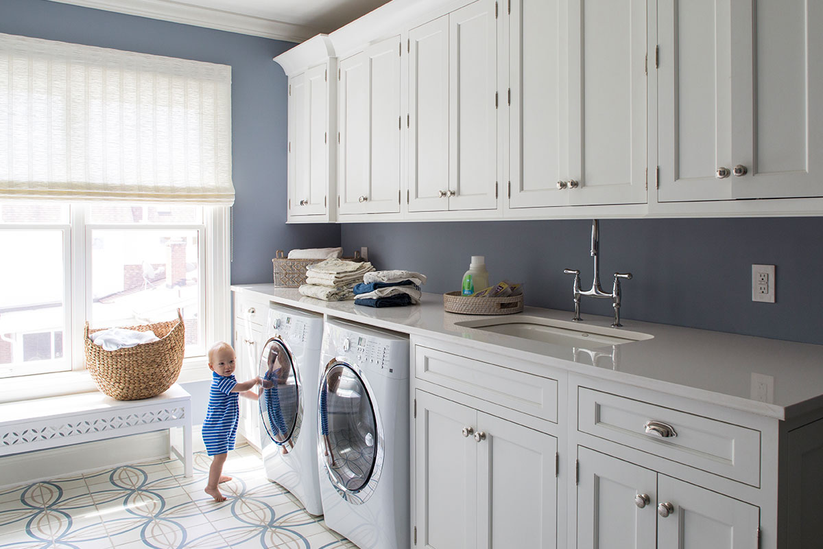 laundry room with little boy and white cabinets and blue walls