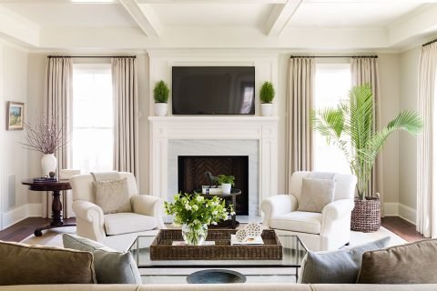 living room with two white chairs and green plants and big windows