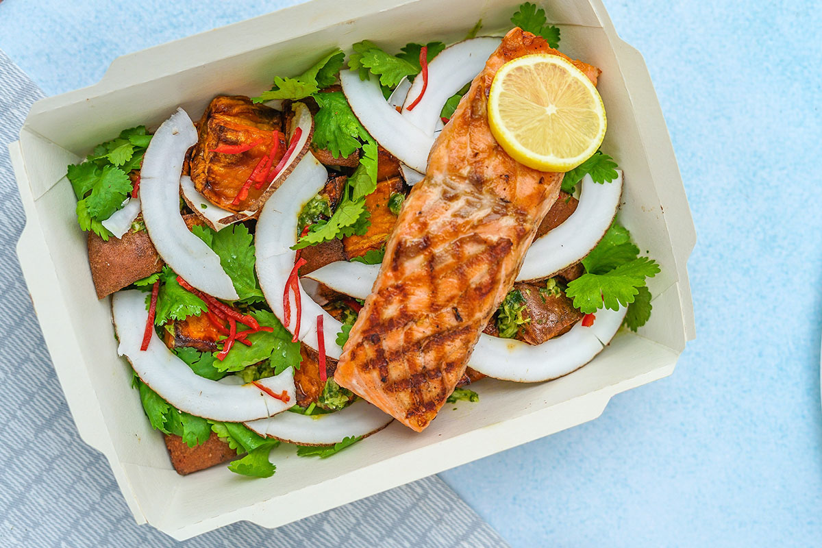 a takeout salad with veggies and salmon on top