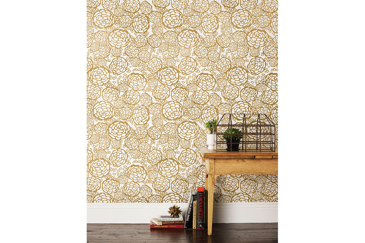 gold flower patterned wallpaper with white background and wooded table and books and metal basket