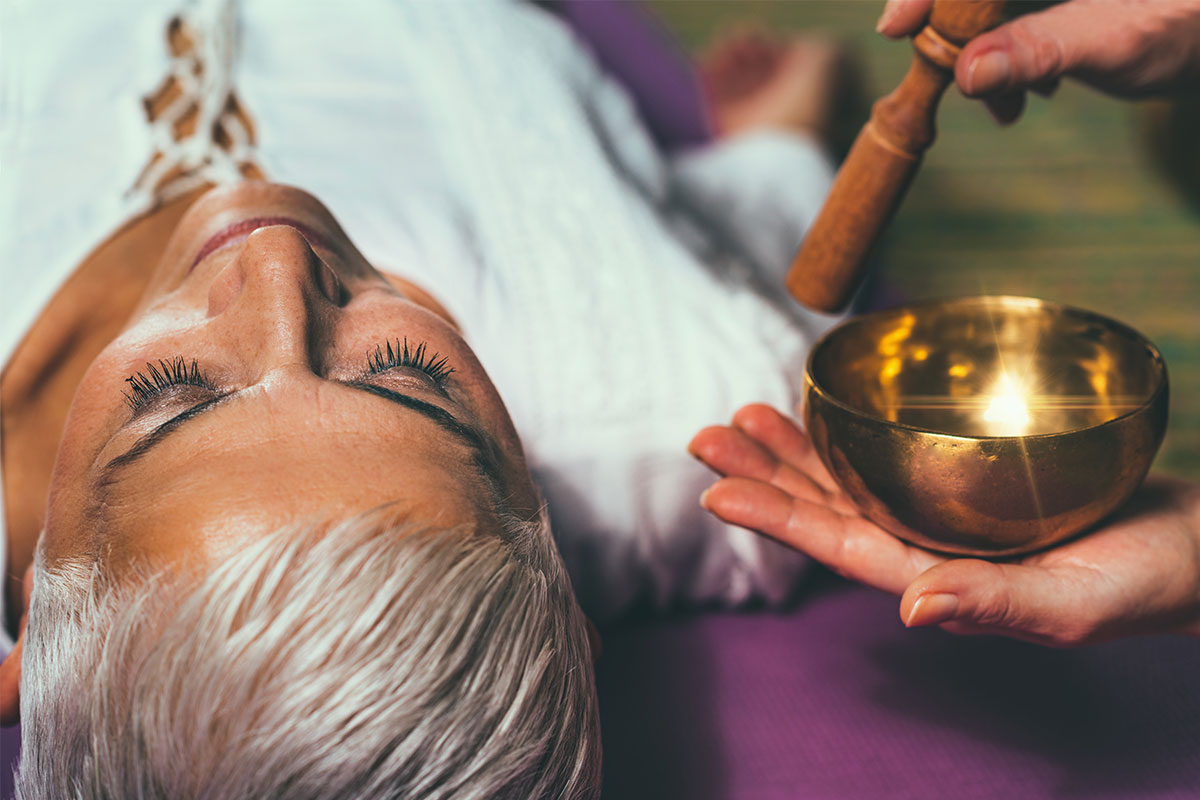 woman laying next to gold sound bowl